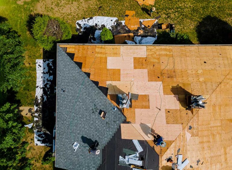 Person in soft-soled shoes carefully stepping across a dry low-slope shingle roof beside a secured ladder.